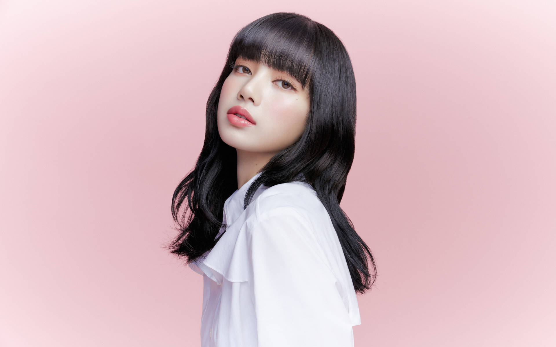 Lalisa 桌布 壁紙 — 一位年輕女性，長長的黑髮和瀏海，穿著白色襯衫，背景是柔和的粉紅色。