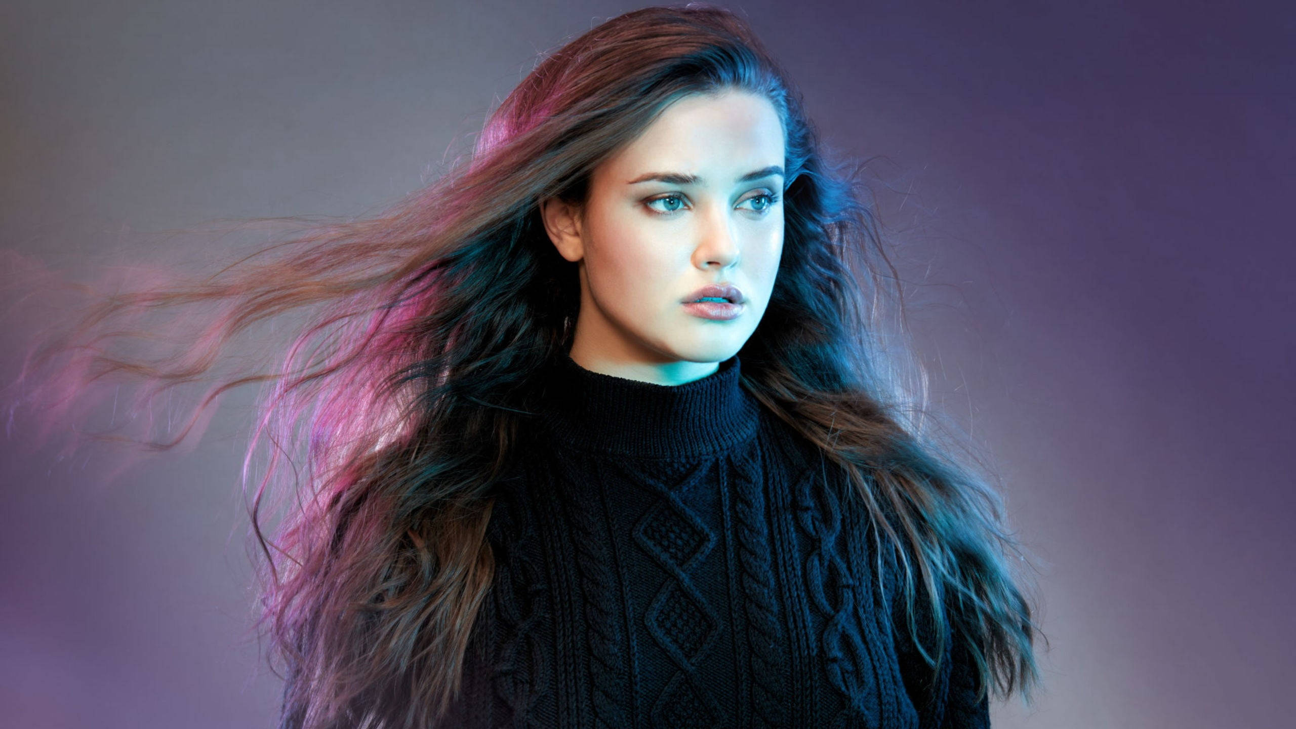 Katherine Langford 桌布 壁紙 — 一位年輕女性，飄逸的頭髮帶有粉紅和藍色條紋，在漸變紫色背景前若有所思地凝視。
