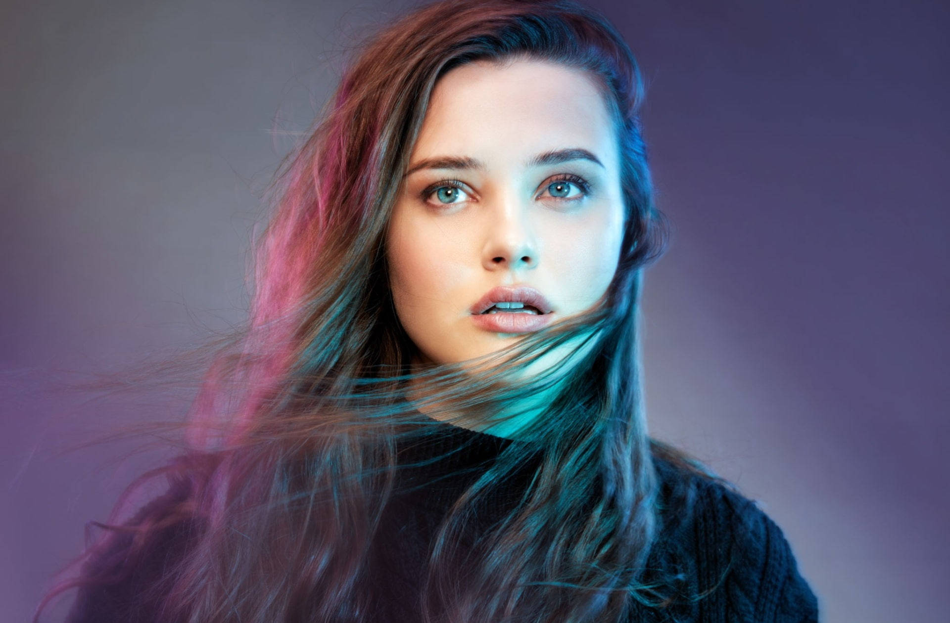 Katherine Langford 桌布 壁紙 — 一位年輕女性，飄逸的頭髮被充滿活力的粉紅色和藍綠色工作室燈光照亮，背景是憂鬱的紫色。