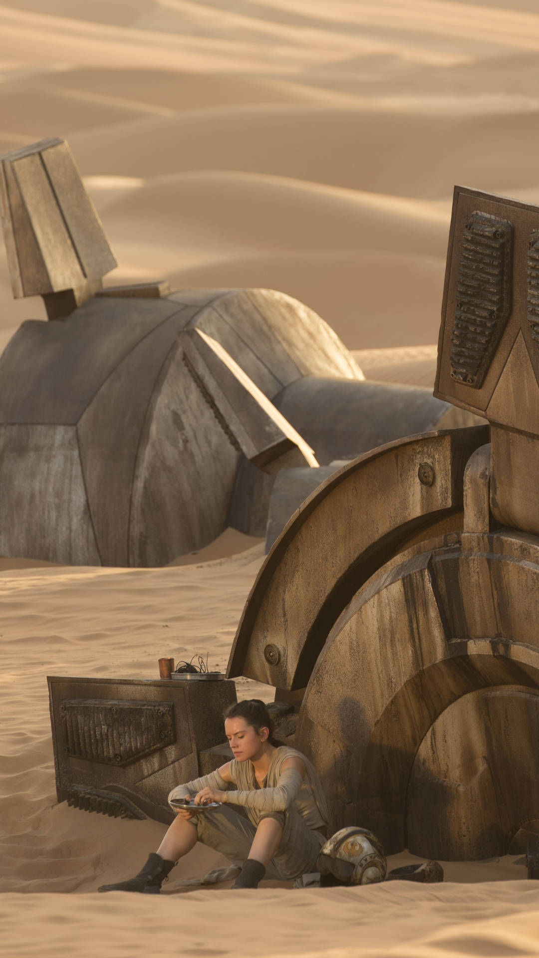 star wars iPhone 6 plus 桌布 壁紙 — 一位年輕女性坐在廣闊沙漠中一個損壞的機器人旁邊，沐浴在溫暖的金色光芒中。