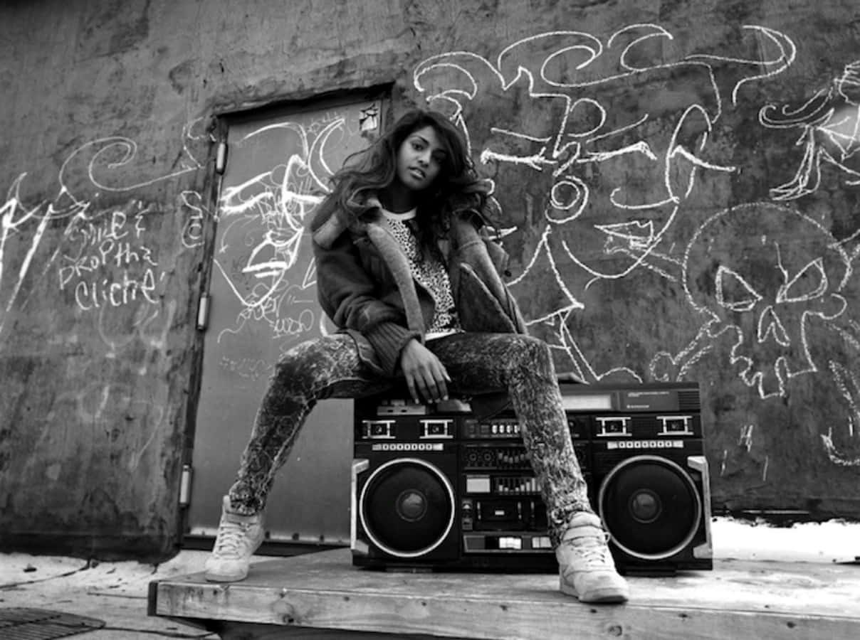 hiphop 桌布 壁紙 — 一位年輕女性坐在復古音箱上，背景是單色塗鴉牆。