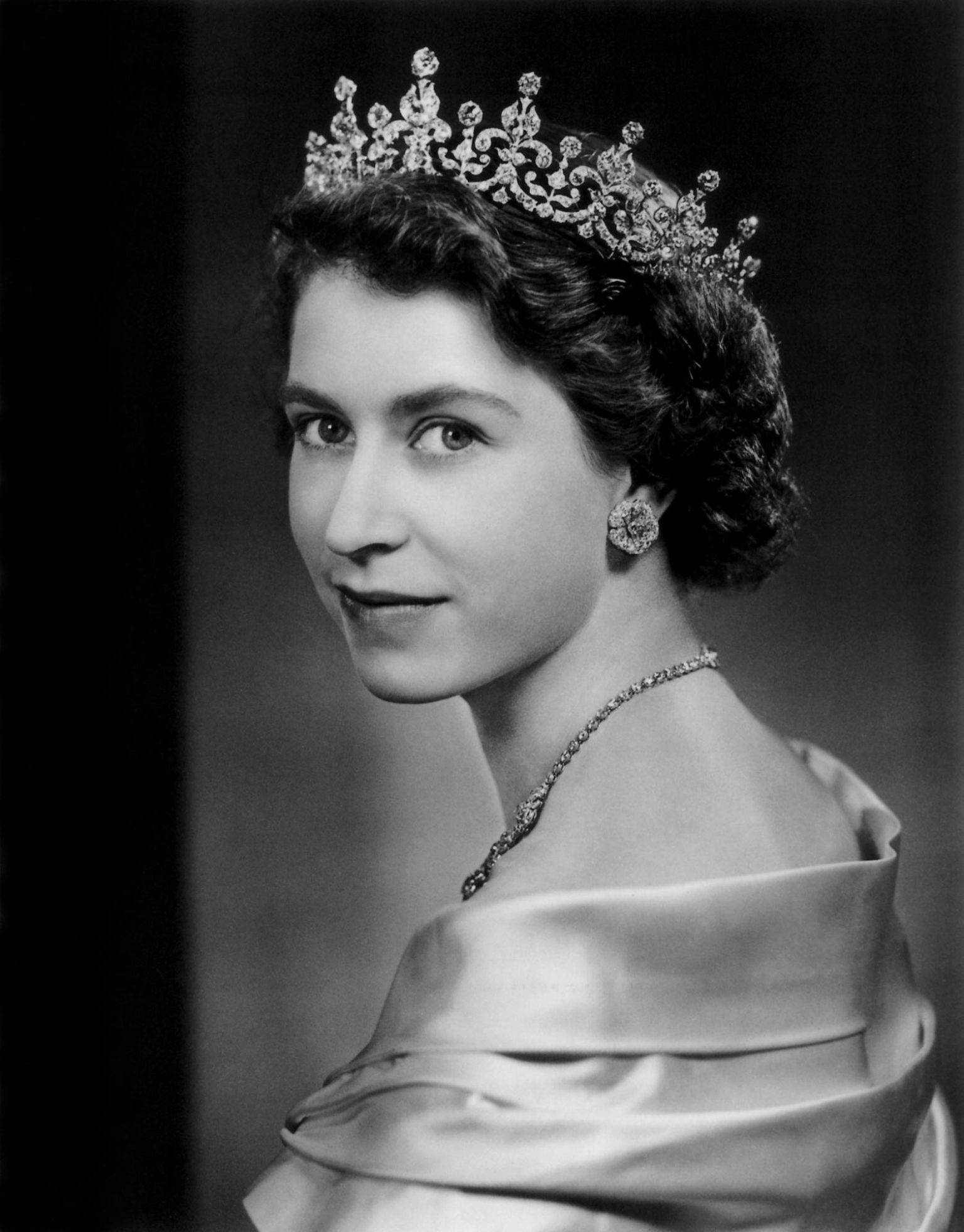 Queen Elizabeth 桌布 壁紙 — 一位年輕女性戴著華麗頭飾和優雅禮服，帶著溫柔微笑的莊嚴黑白肖像。