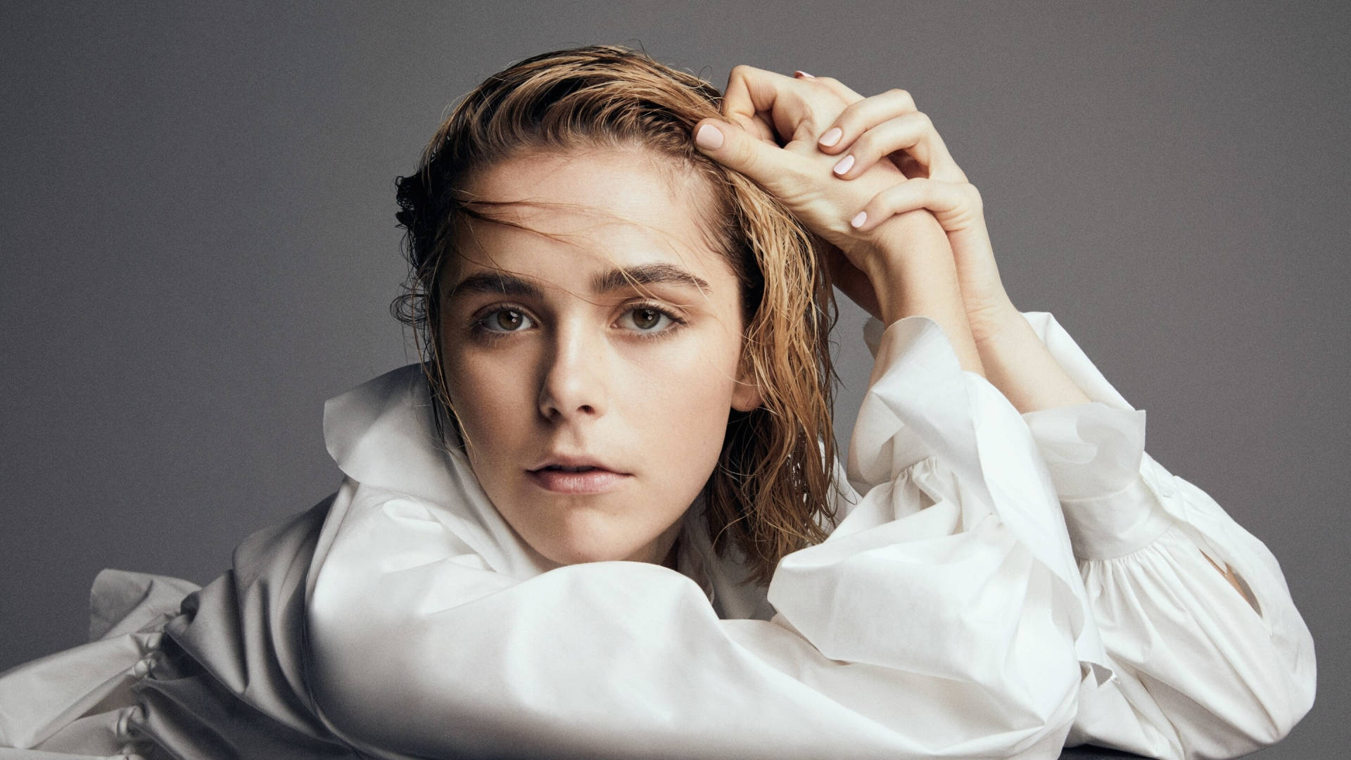 Kiernan Shipka 桌布 壁紙 — 一位年輕女性濕髮穿著白色襯衫，在灰色背景前直視鏡頭。