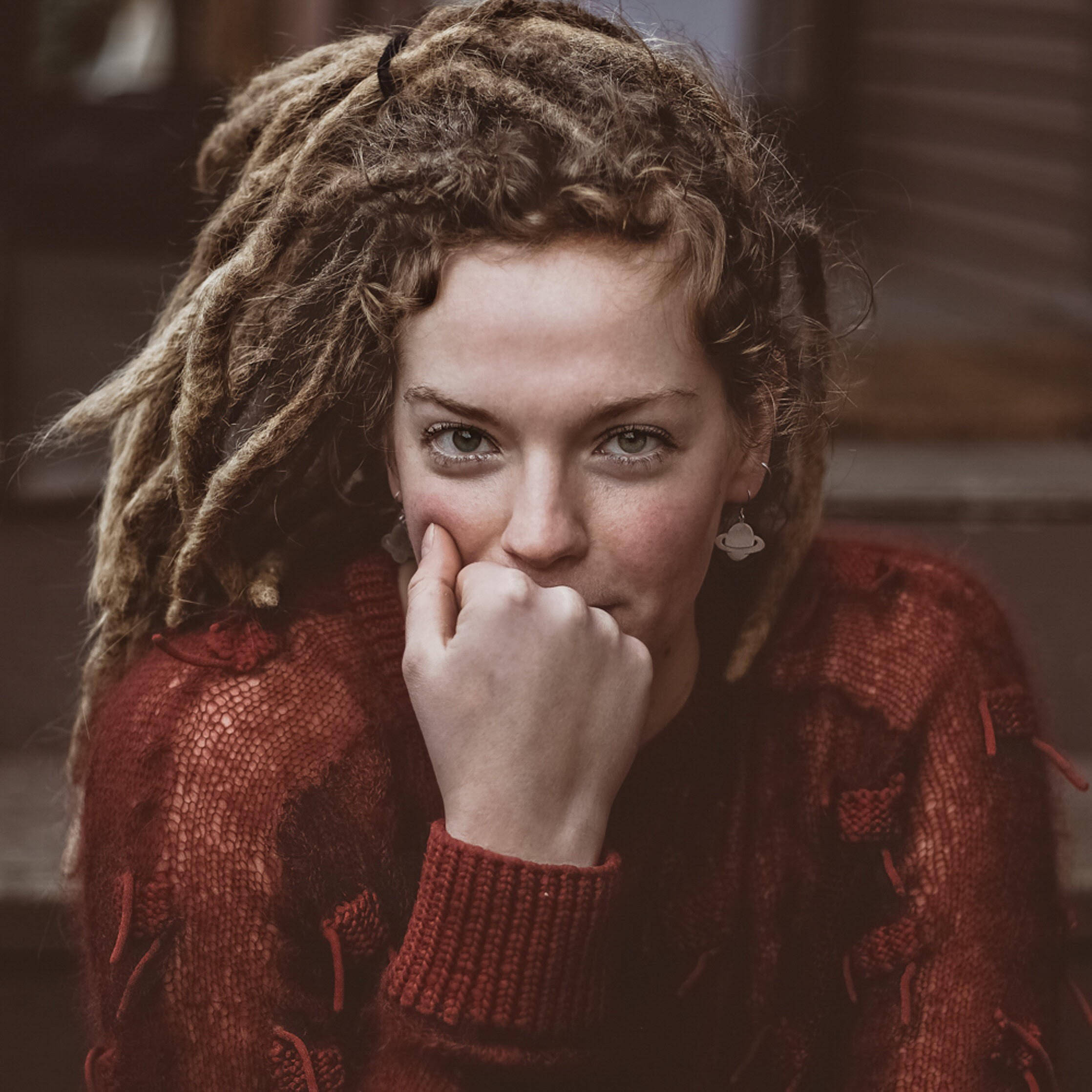 Woman 桌布 壁紙 — 一位年輕女性留著捲曲辮子，身穿紅色針織毛衣，手托下巴，若有所思地凝視著。