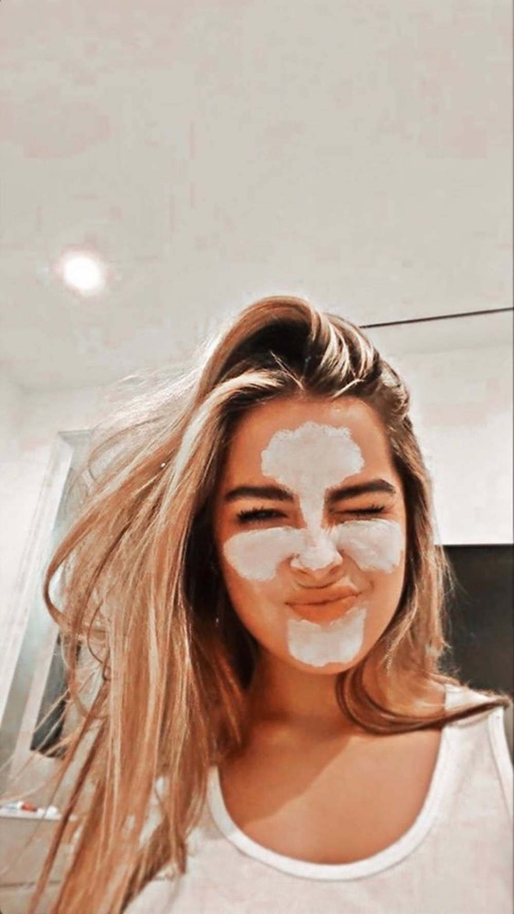 Celebrity 桌布 壁紙 — 一位年輕女性留著金色長髮，在明亮的浴室裡戴著白色黏土面膜，頑皮地微笑。