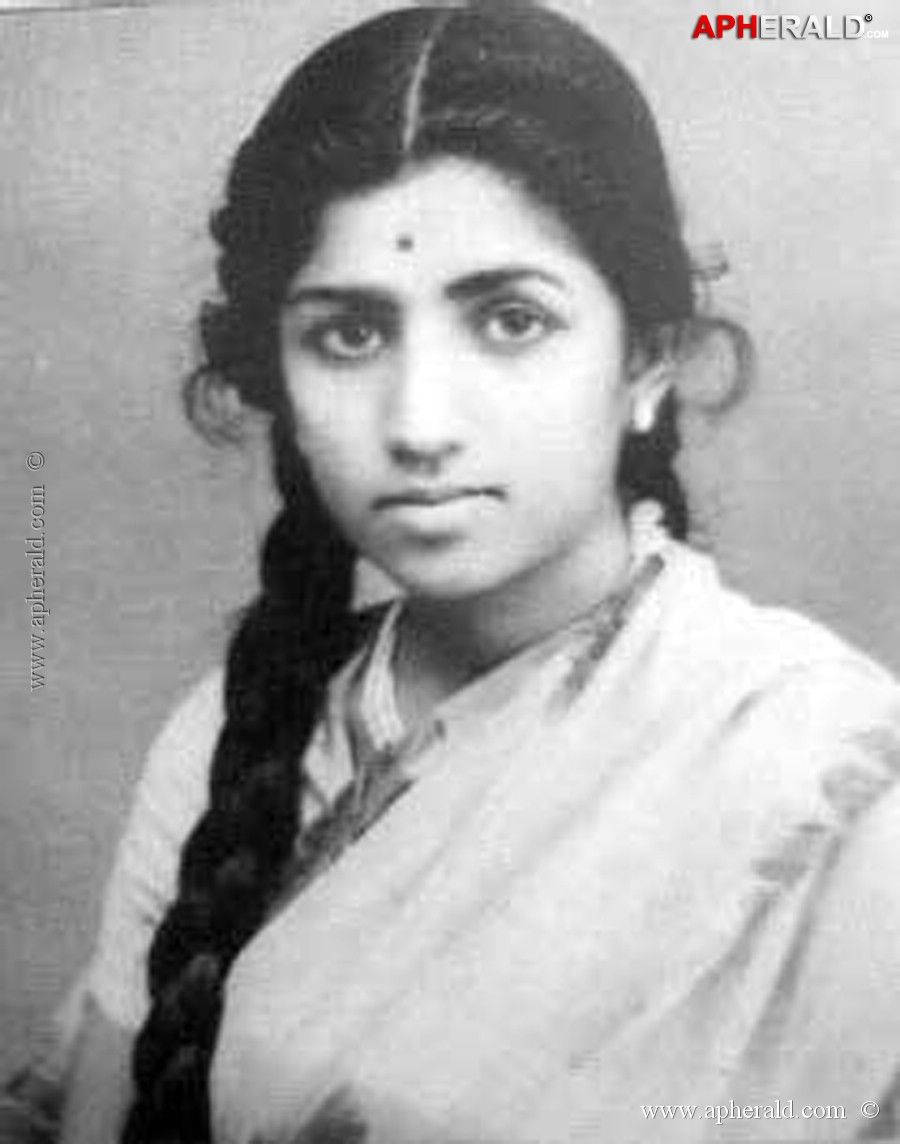 Lata Mangeshkar 桌布 壁紙 — 一位年輕女性留著長辮子、額頭點著紅點，直視鏡頭的復古黑白肖像。