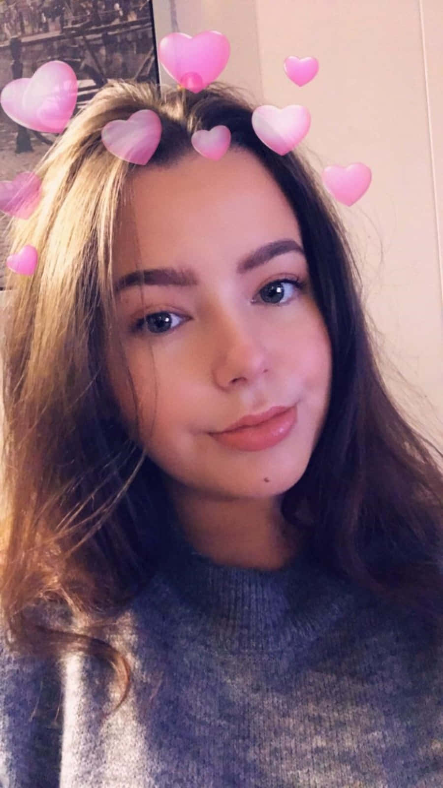 Snapchat 桌布 壁紙 — 一位年輕女性留著長長棕色頭髮，在自拍中微笑，粉紅色心形表情符號漂浮在她頭部周圍。
