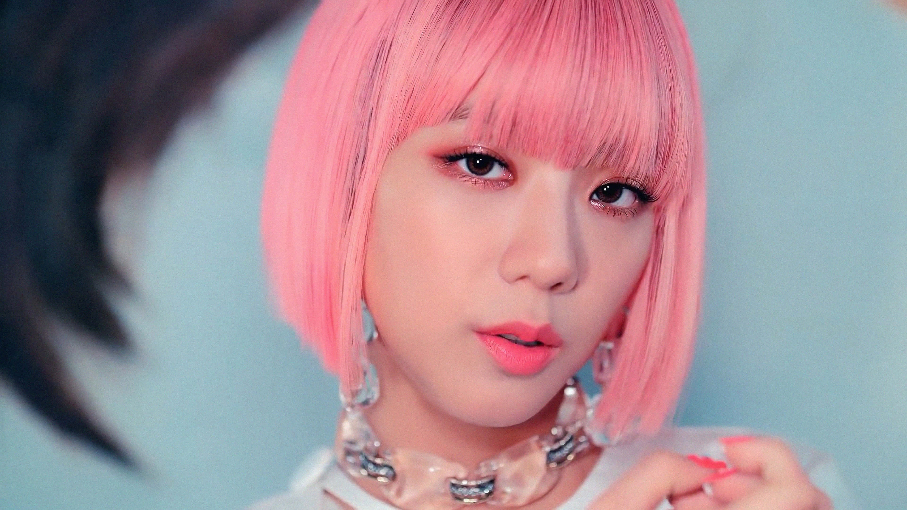 BLACKPINK 桌布 壁紙 — 一位年輕女性的特寫肖像，擁有充滿活力的粉紅色鮑伯頭和鮮豔妝容，背景是柔和的藍色。