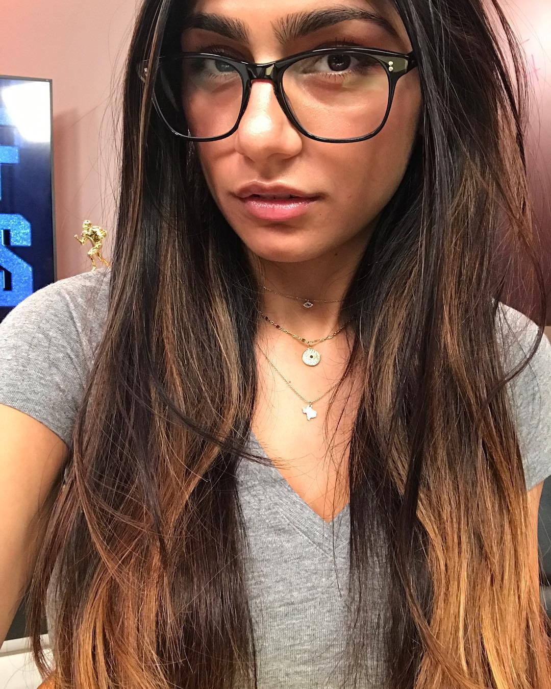 戴眼鏡、長髮分層的年輕女性，身穿灰色上衣，佩戴多層項鍊。 — 漂亮的動圖 壁紙