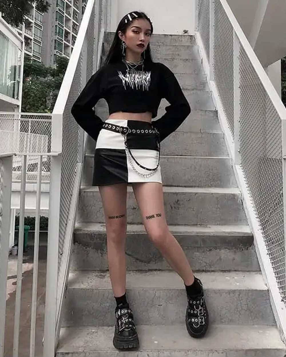 Trendy Aesthetic 桌布 壁紙 — 一位年輕女性穿著前衛的黑白服裝，在帶有白色欄杆的混凝土樓梯上自信地擺姿勢。
