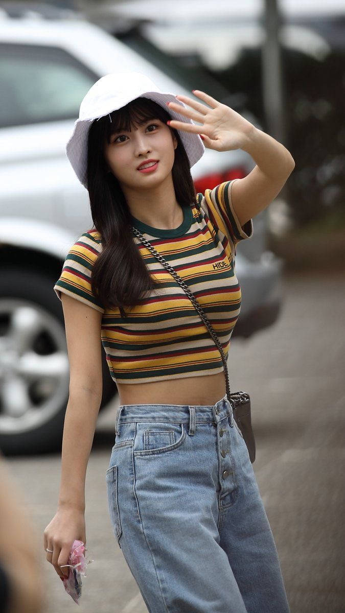 Momo 桌布 壁紙 — 一位年輕女性穿著條紋露臍上衣和牛仔褲，戴著白色漁夫帽在戶外愉快地揮手。