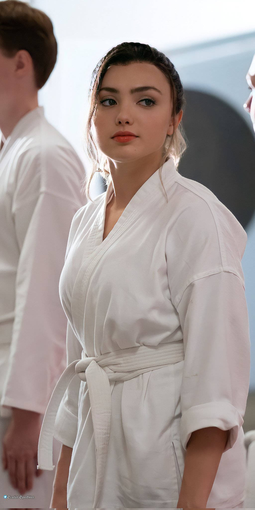 Cobra Kai Phone 桌布 壁紙 — 一位年輕女性穿著潔白的空手道服，在明亮的道場中以專注的姿態站立。