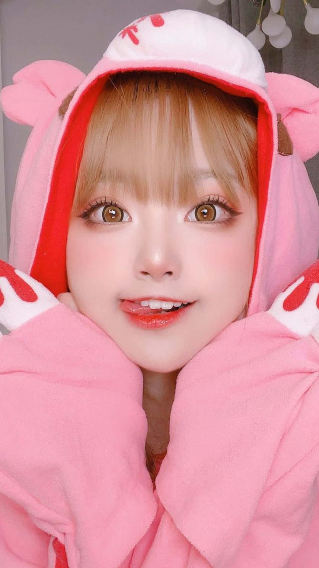 Cosplay Anime Kawaii 桌布 壁紙 — 一位年輕女性穿著粉紅色兔子連體衣，在明亮的妝容和柔和燈光下對著鏡頭溫暖微笑。