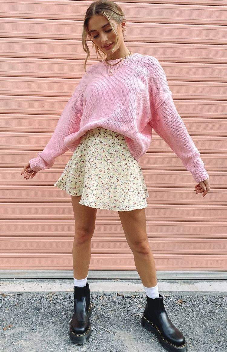 Trendy Aesthetic 桌布 壁紙 — 一位年輕女性穿著粉紅色毛衣和花卉裙，在粉紅色波紋牆前隨意擺姿勢。