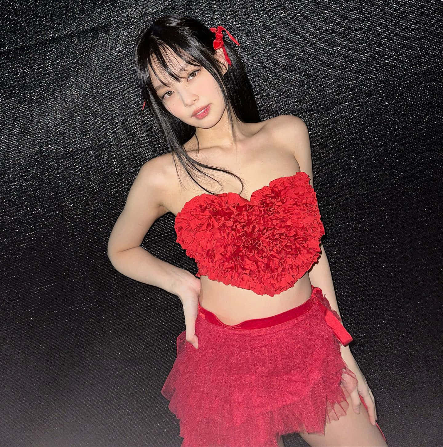 BLACKPINK 桌布 壁紙 — 一位年輕女性穿著鮮紅色心形上衣和層疊裙，在深色紋理背景前自信地擺姿勢。