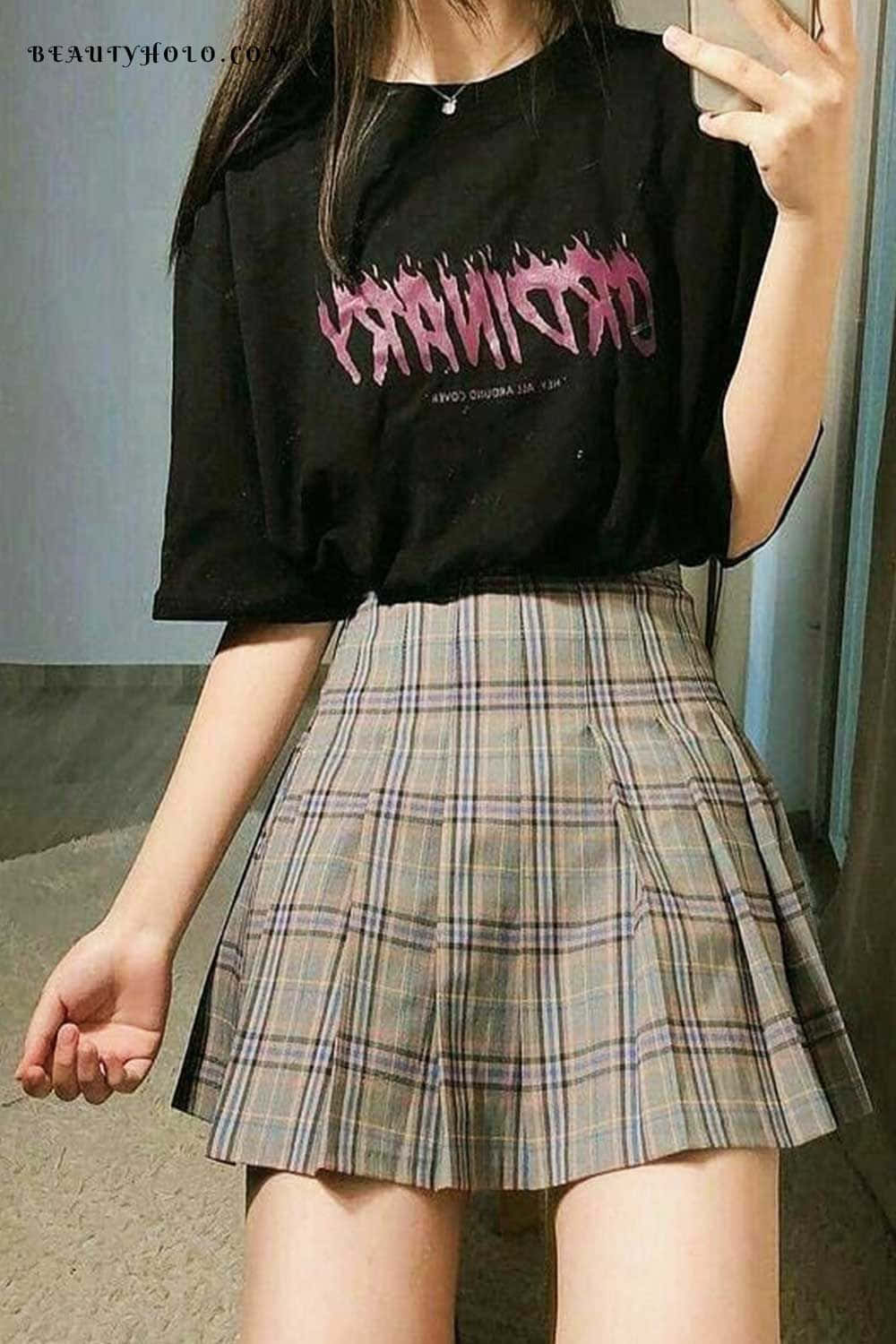 emo 美學 桌布 壁紙 — 一位年輕女性穿著黑色圖案T恤和格子百褶裙，在室內對著鏡子自拍。