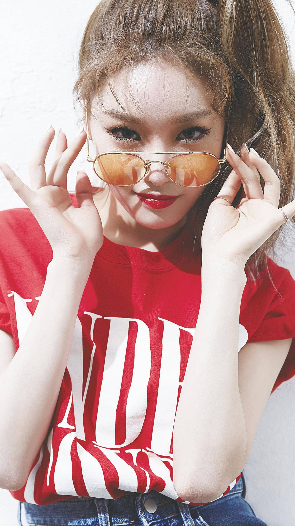 Chungha 桌布 壁紙 — 一位年輕女性紮著高馬尾，戴著橙色太陽眼鏡，自信地靠著純白牆壁，身穿紅色圖案T恤。