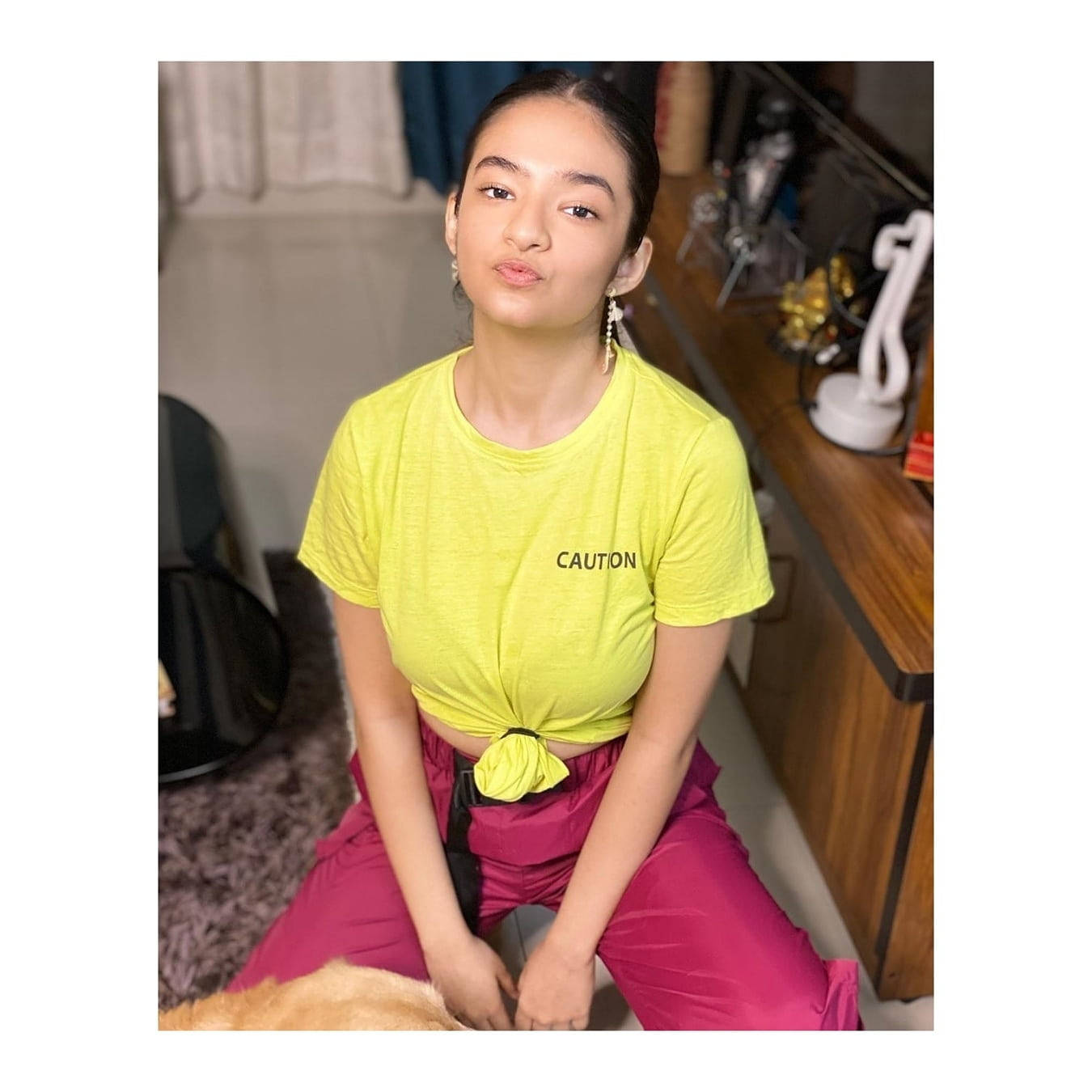 Indian 桌布 壁紙 — 一位年輕女性身穿亮黃色短版上衣和洋紅色褲子，帶著俏皮的表情坐在室內。