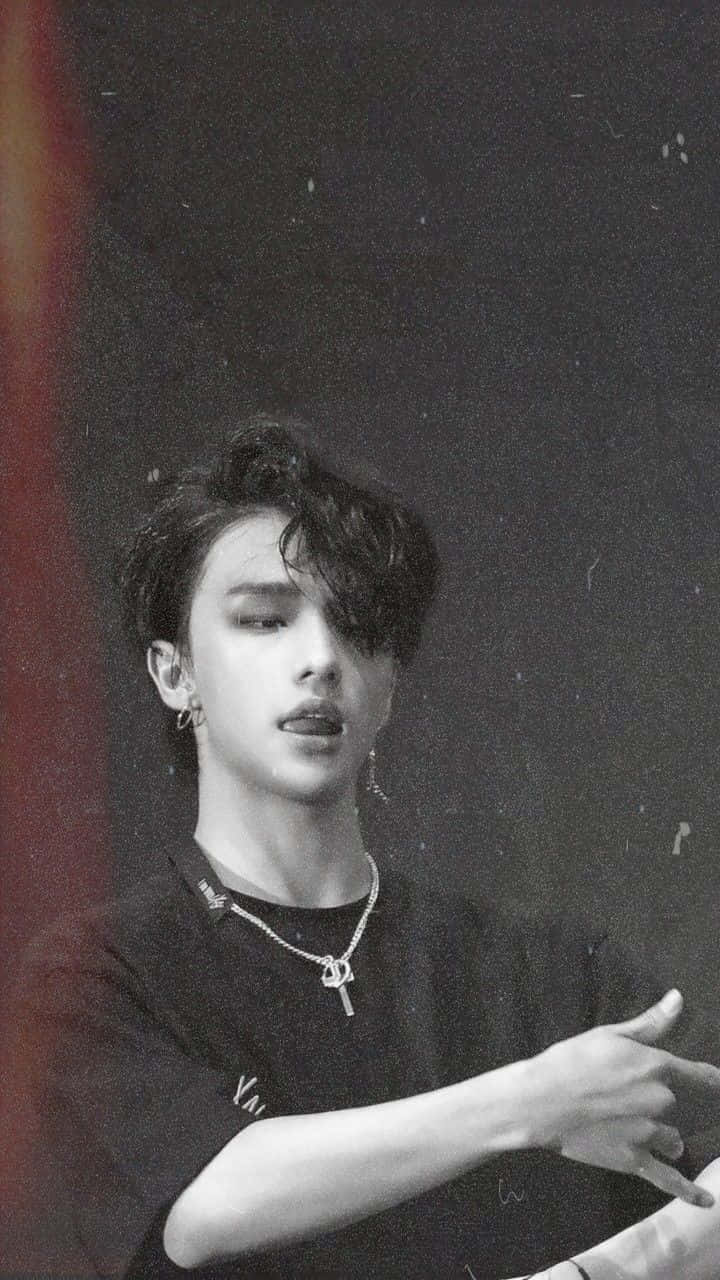 hyunjin 桌布 壁紙 — 一位年輕男子，擁有造型頭髮和珠寶，在顆粒狀的黑白肖像中，背景黑暗，手指向前方。
