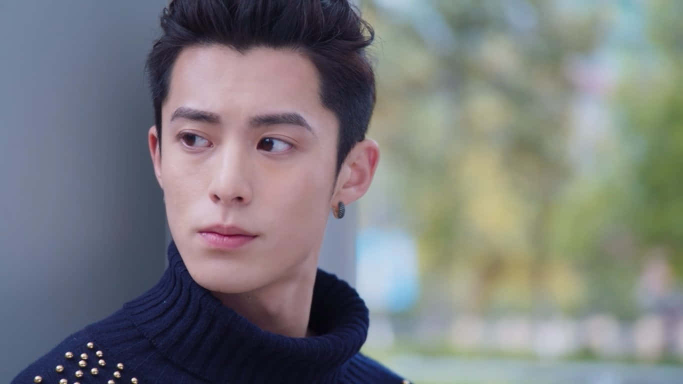 Dylan Wang 桌布 壁紙 — 一位年輕男子，留著時尚的深色頭髮，戴著金色耳釘，身穿海軍藍高領毛衣，若有所思地望向一旁。