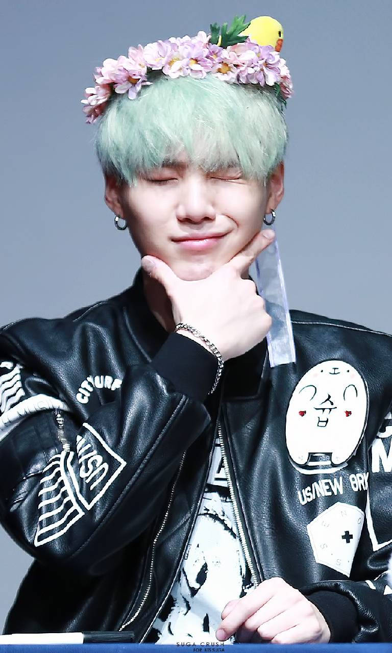 Cute Bts 桌布 壁紙 — 一位年輕男子，留著薄荷綠的頭髮，戴著花冠，穿著帶有補丁的黑色皮夾克，溫柔地微笑。