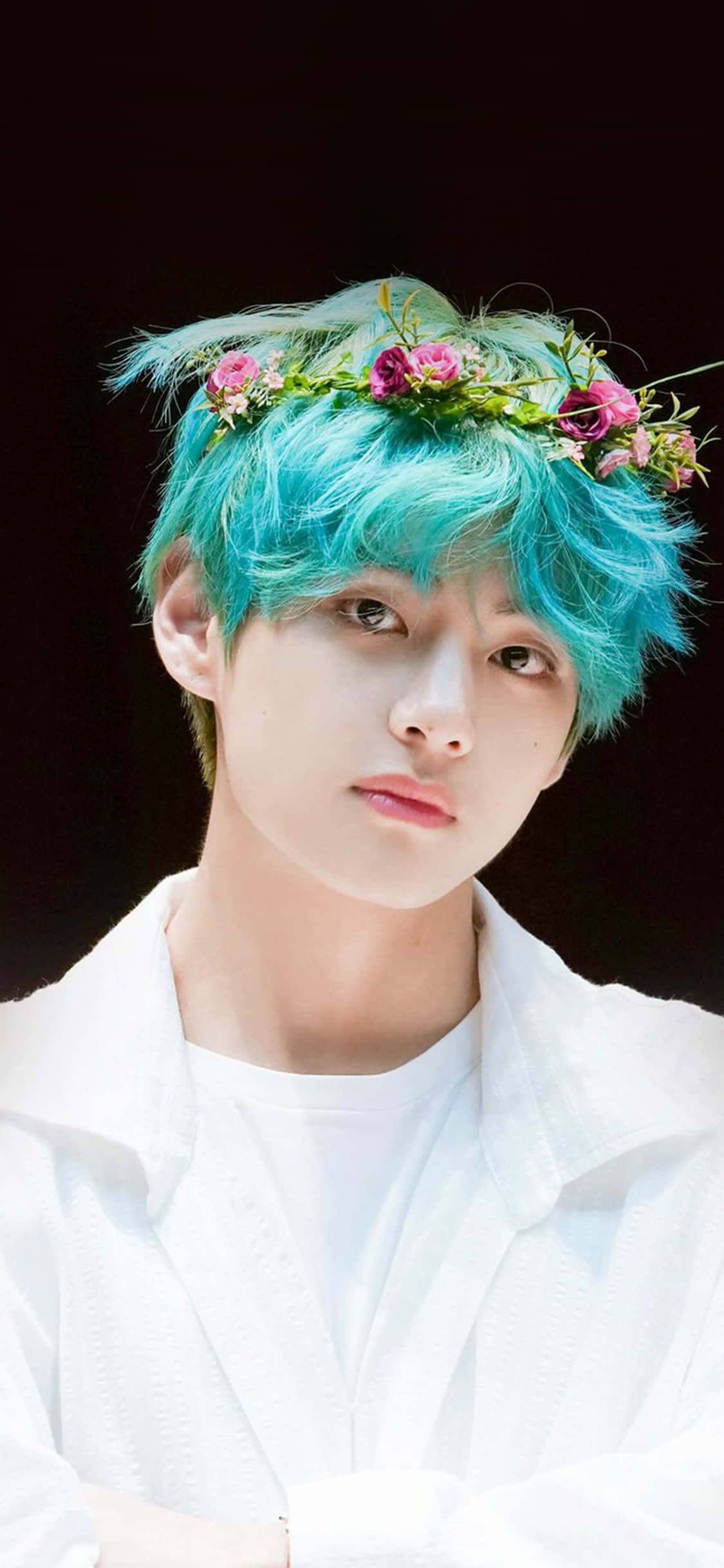 BTS V 動圖 桌布 壁紙 — 一位年輕男子擁有充滿活力的藍綠色頭髮，飾以粉紅色花冠，在深色背景下溫柔地凝視。