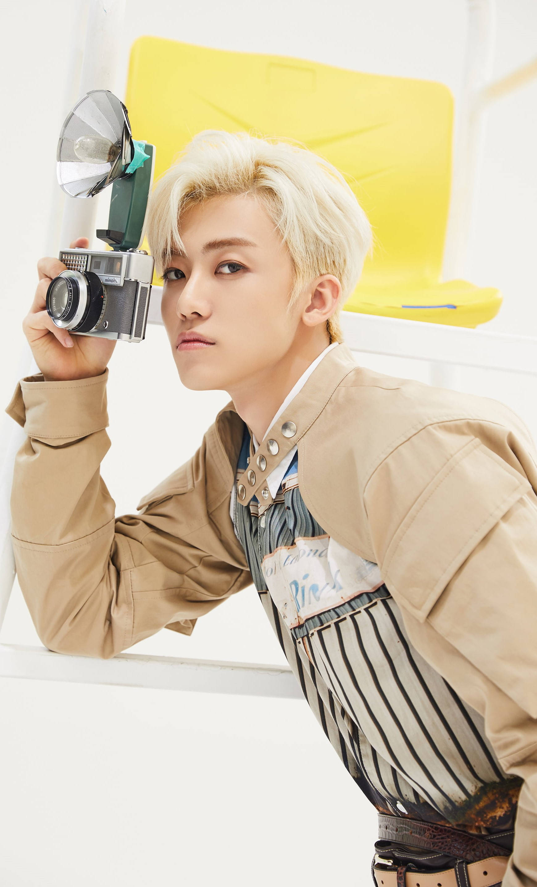 jaemin 桌布 壁紙 — 一位年輕男子擁有鉑金色頭髮，在明亮的白色和黃色背景前手持復古相機。