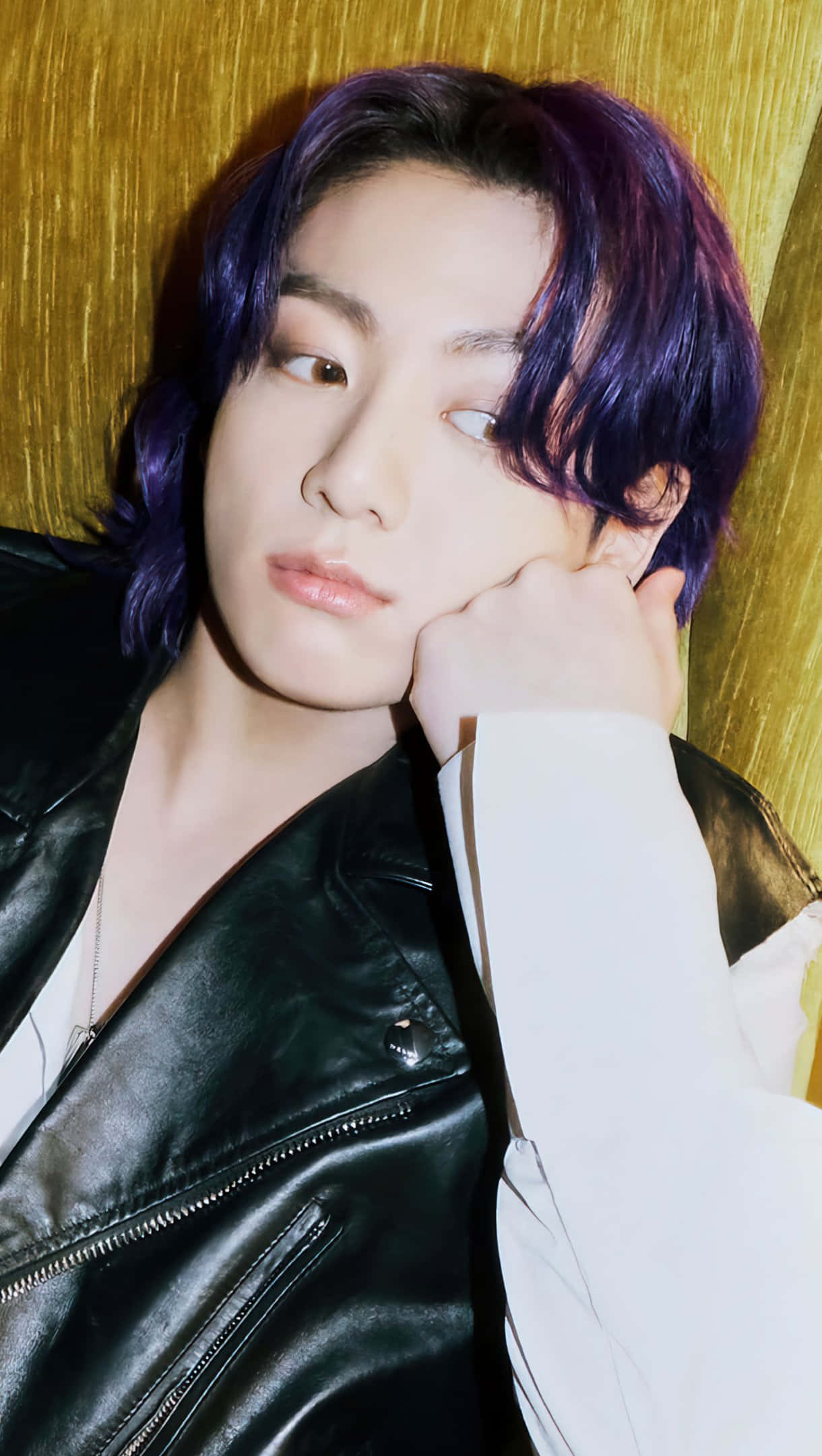 Jungkook 桌布 壁紙 — 一位年輕男子擁有鮮豔紫色頭髮，穿著黑色皮夾克，在紋理金色背景上將頭靠在手上。