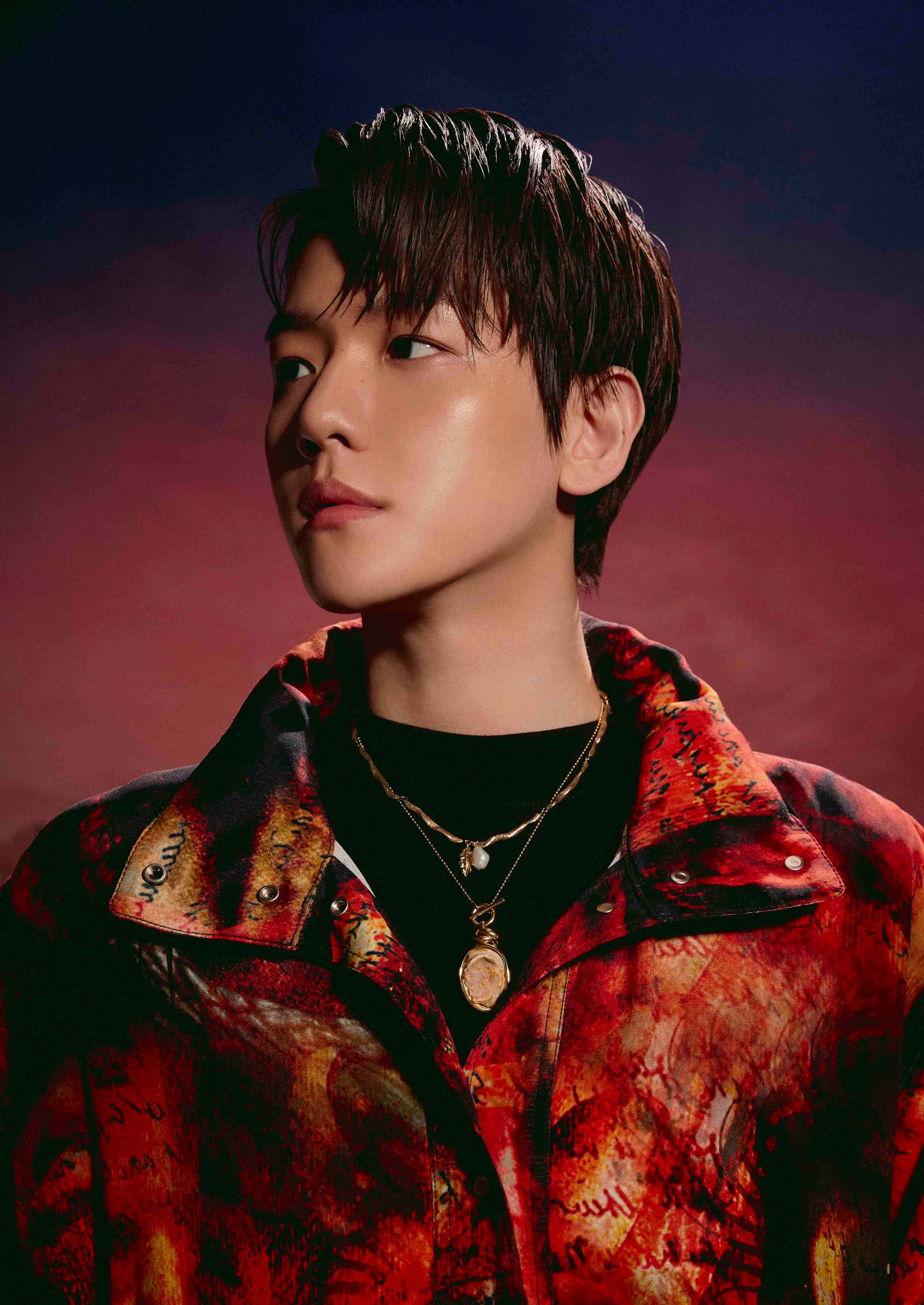 EXO 桌布 壁紙 — 一位年輕男子梳著深色時尚髮型，穿著鮮豔的紅色圖案外套，背景是帶有氛圍感的紫色和紅色漸變色。