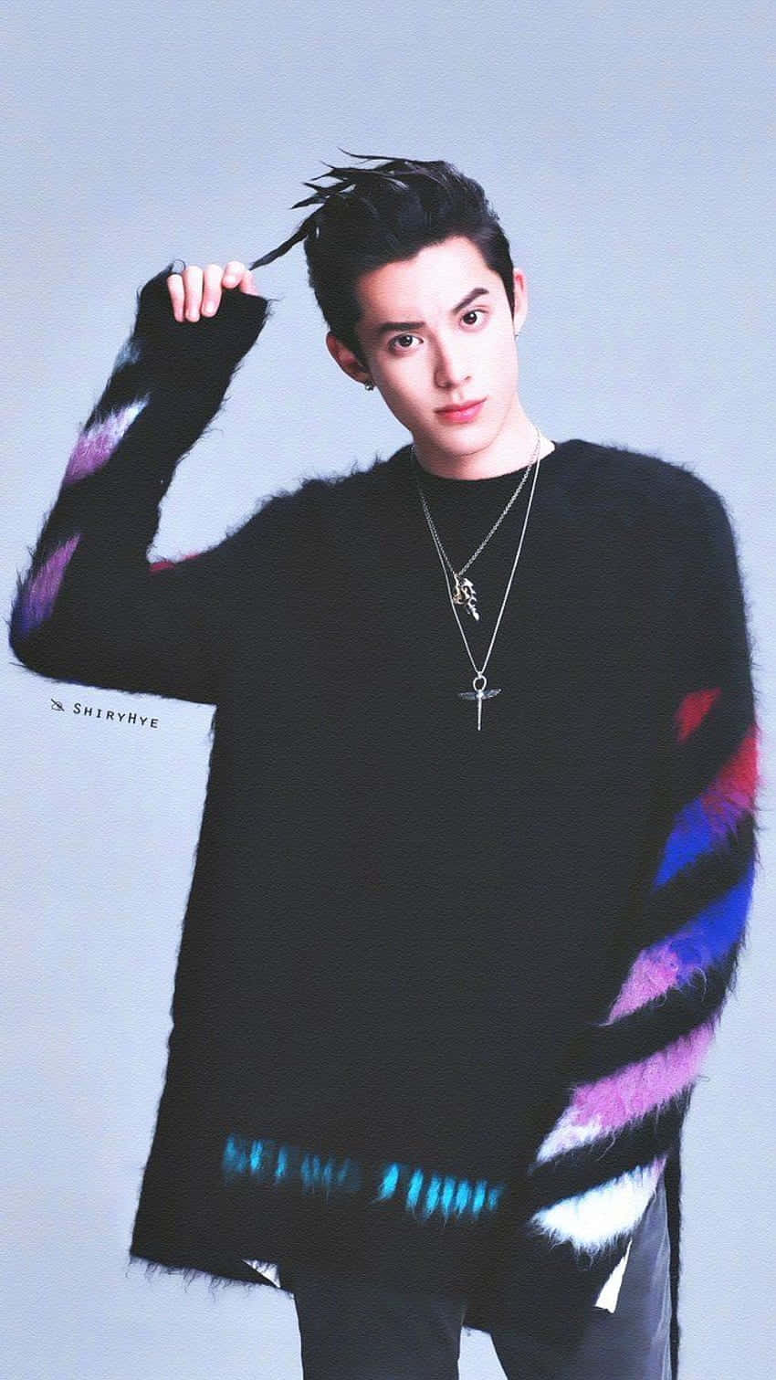Dylan Wang 桌布 壁紙 — 一位年輕男子留著刺蝟頭，身穿帶有彩色條紋袖子的黑色毛絨毛衣，在純灰色背景前自信地擺姿勢。