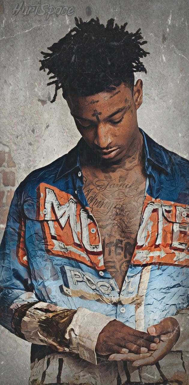 21 Savage 桌布 壁紙 — 一位年輕男子留著辮子頭和刺青，穿著破損的牛仔外套，背景是風化的磚牆。