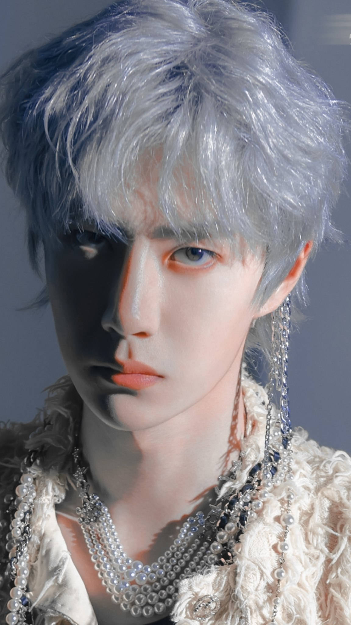 王一博 桌布 壁紙 — 一位年輕男子的特寫肖像，他擁有銀色頭髮和引人注目的藍色眼睛，在柔和的灰色背景前佩戴著多層珍珠項鍊。