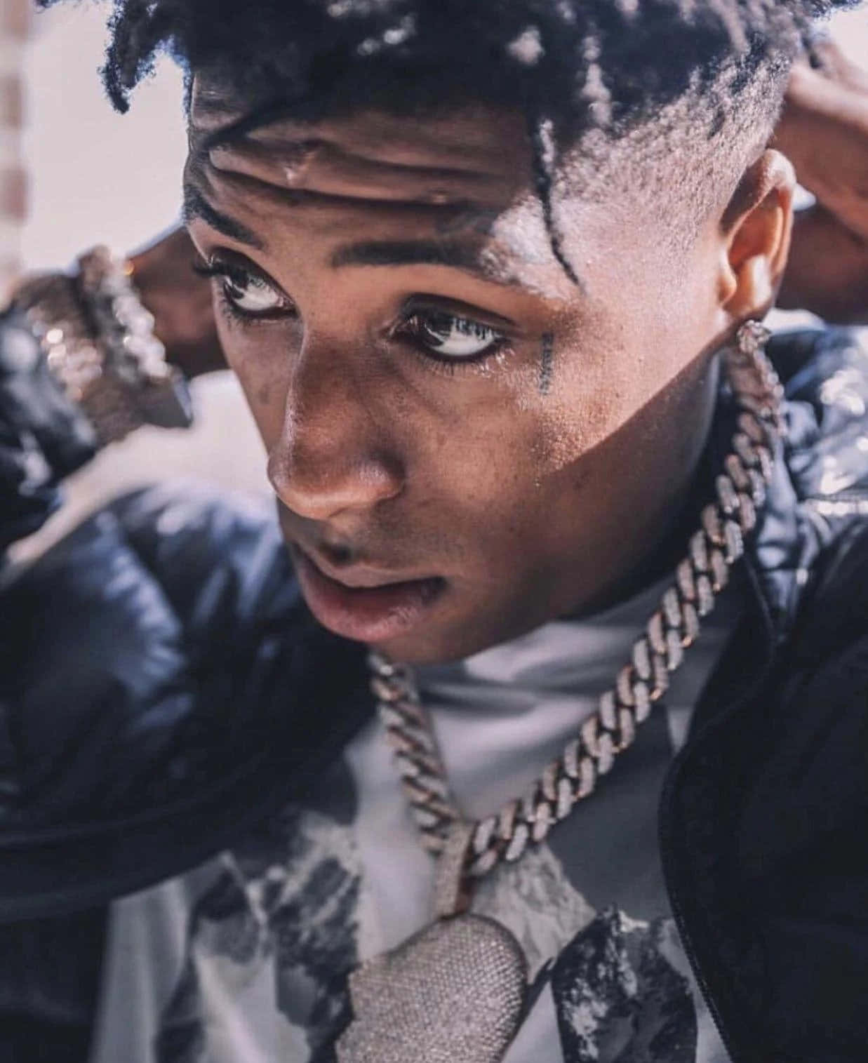 NBA YoungBoy 桌布 壁紙 — 一位年輕男子的特寫肖像，他梳著辮子，戴著鑲鑽鏈條項鍊，專注地凝視鏡頭。