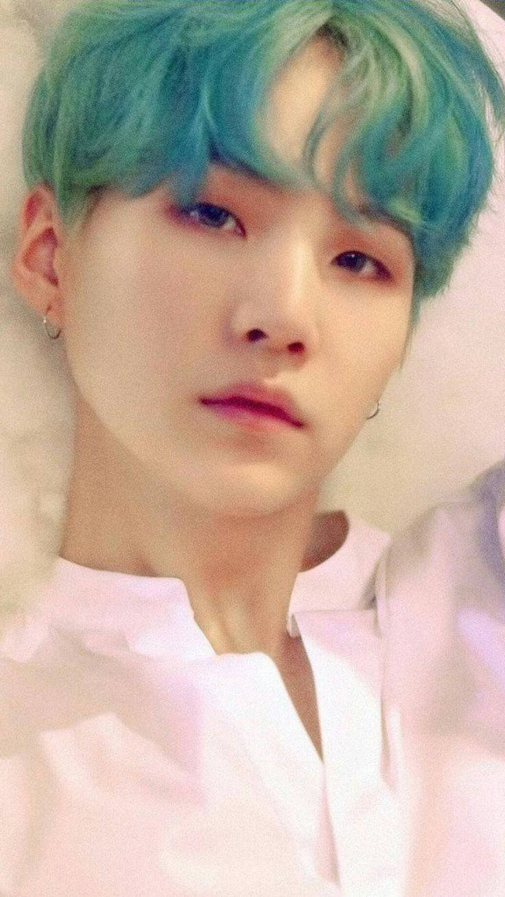 Suga Bts 桌布 壁紙 — 一位年輕男子的特寫肖像，擁有鮮豔的藍綠色頭髮和柔和粉紅燈光，身穿白色襯衫和小圈耳環。