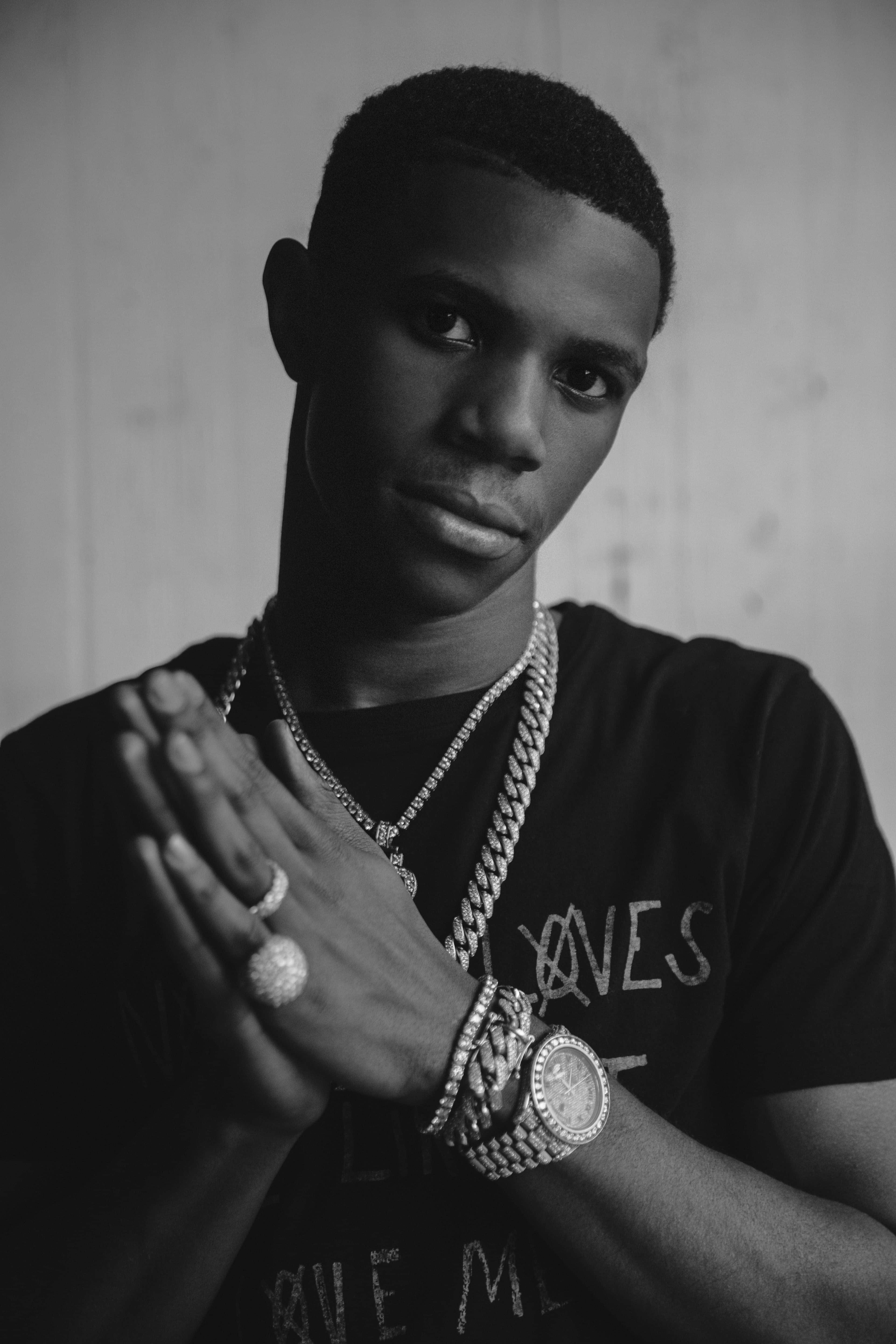 Rappers 桌布 壁紙 — 一位年輕男子的黑白肖像，神情嚴肅，佩戴多條鑲鑽鏈條、戒指和手錶，雙手緊握。