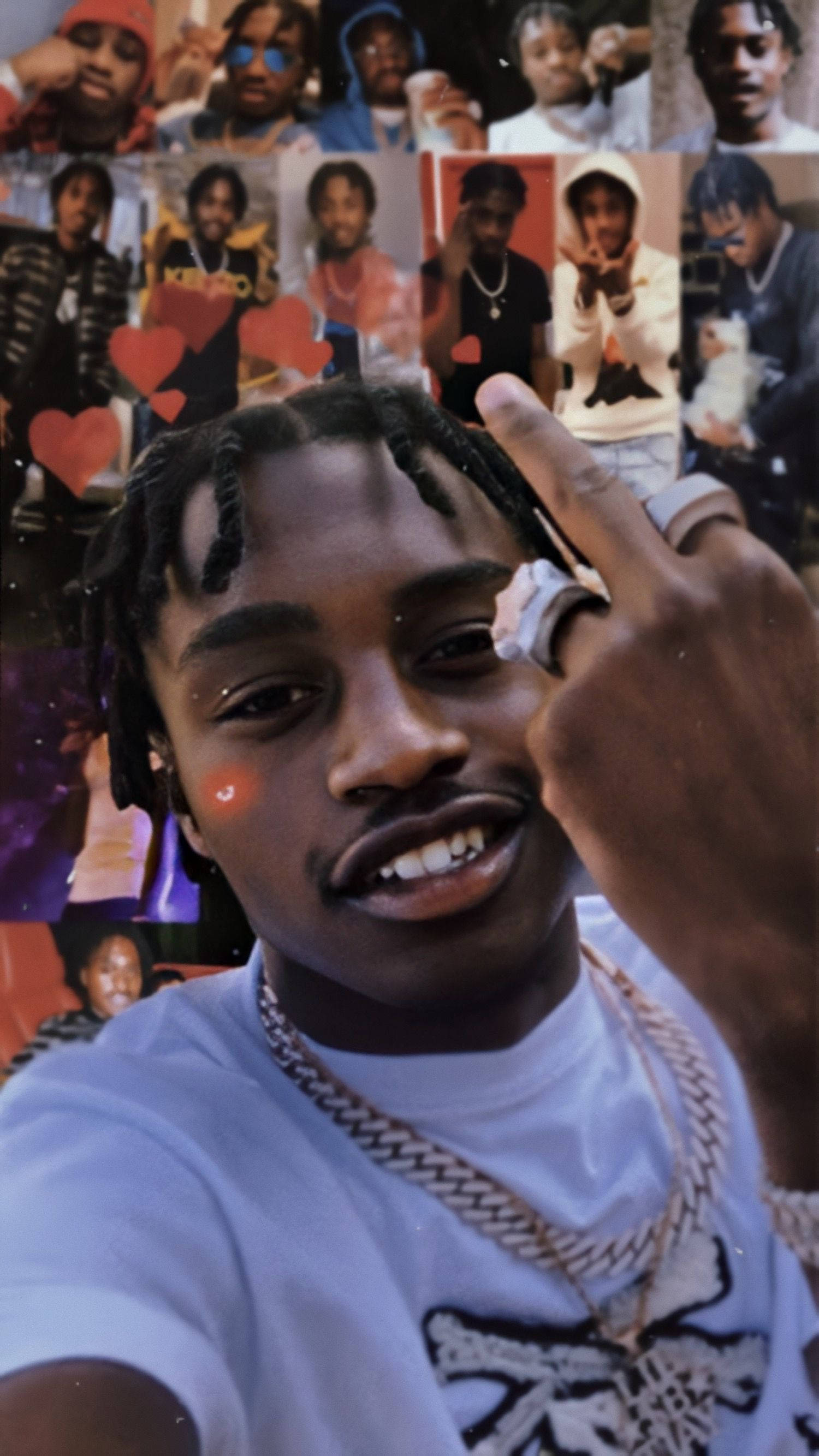 Lil Tjay 桌布 壁紙 — 一位年輕男子紮著辮子，戴著金鏈，在自己照片的拼貼畫前比出和平手勢，周圍有紅色心形。