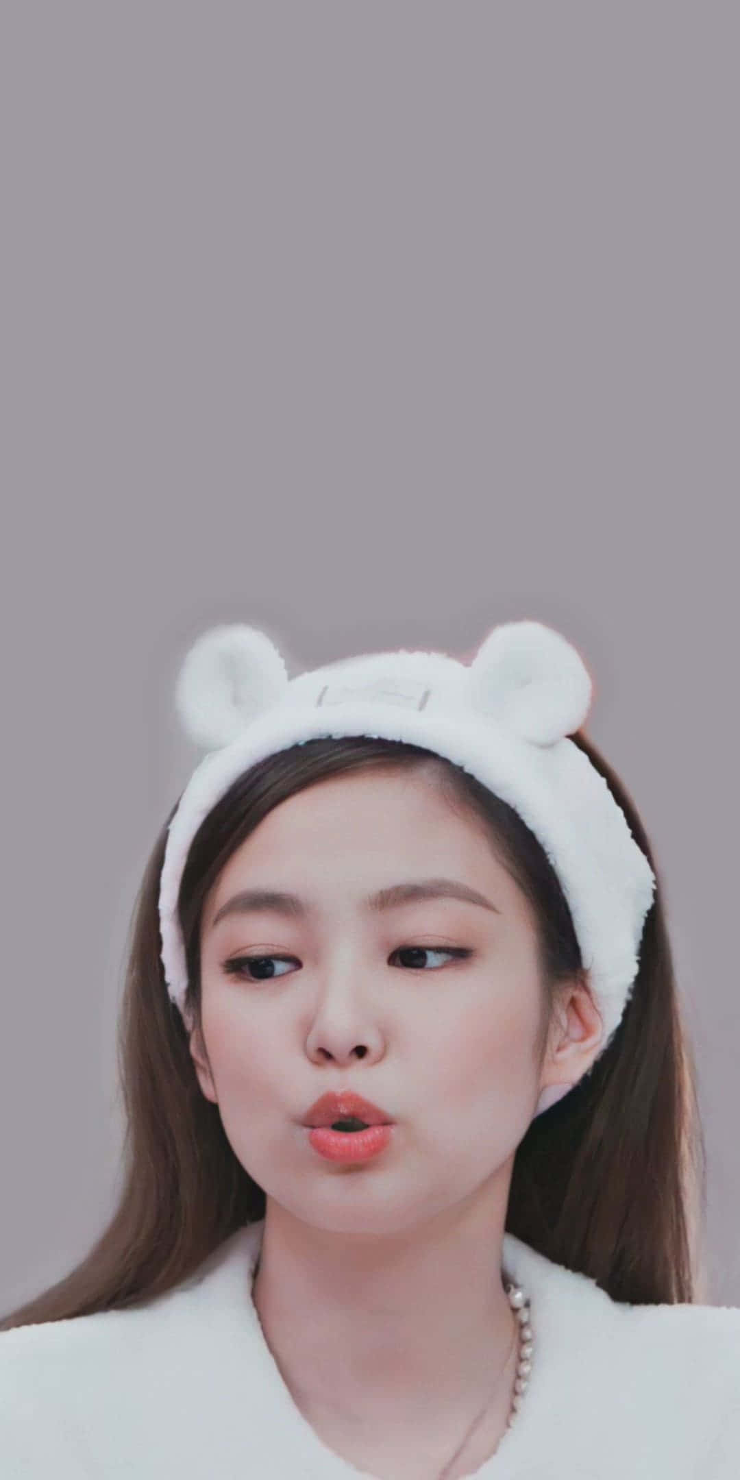 BLACKPINK 桌布 壁紙 — 一位年輕的棕髮女性戴著毛茸茸的白色熊耳頭帶，在純灰色背景前做出俏皮的嘟嘴表情。