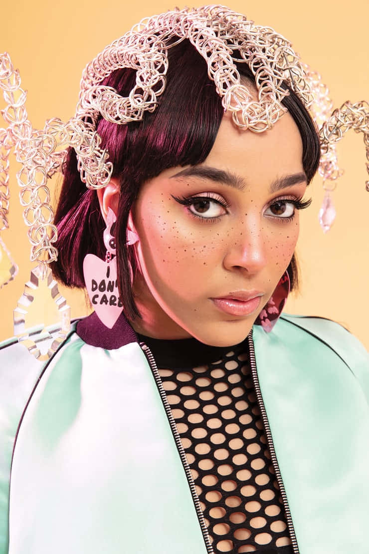 Doja Cat 桌布 壁紙 — 一位年輕的紫髮女性，在溫暖的黃色背景下，戴著金屬鏈頭飾和心形耳環。
