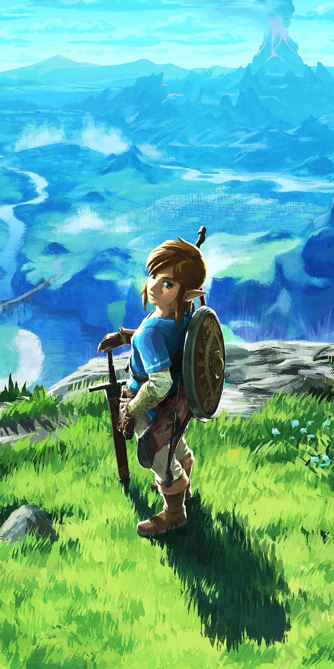 Zelda Phone 桌布 壁紙 — 一位年輕英雄手持劍與盾，站在長滿青草的懸崖上，俯瞰著廣闊的藍色景觀，遠方有山脈和冒煙的火山。