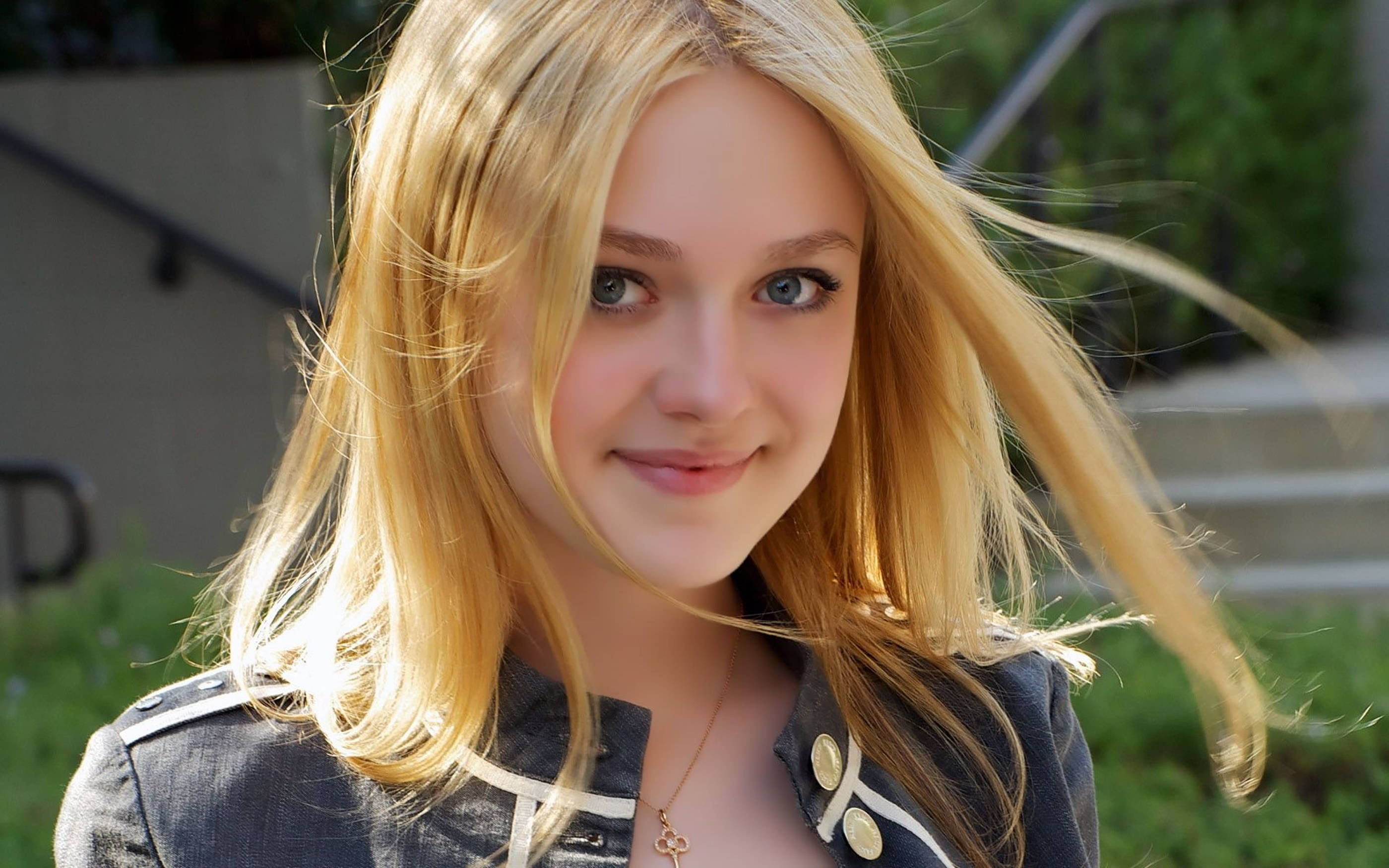 Celebrity 桌布 壁紙 — 一位年輕金髮女子帶著溫柔的微笑看著鏡頭，陽光在戶外突顯她飄逸的秀髮。