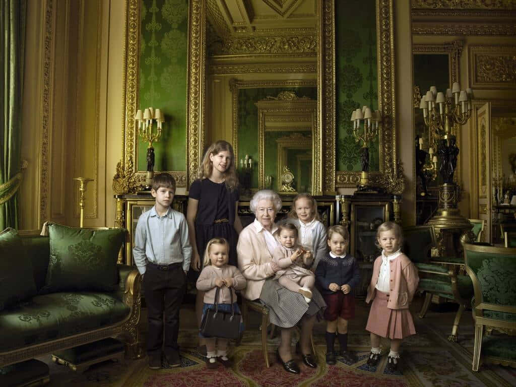 Queen Elizabeth 桌布 壁紙 — 一位年長女士威嚴地坐在鍍金房間中，被七名身穿正裝的孩子圍繞。