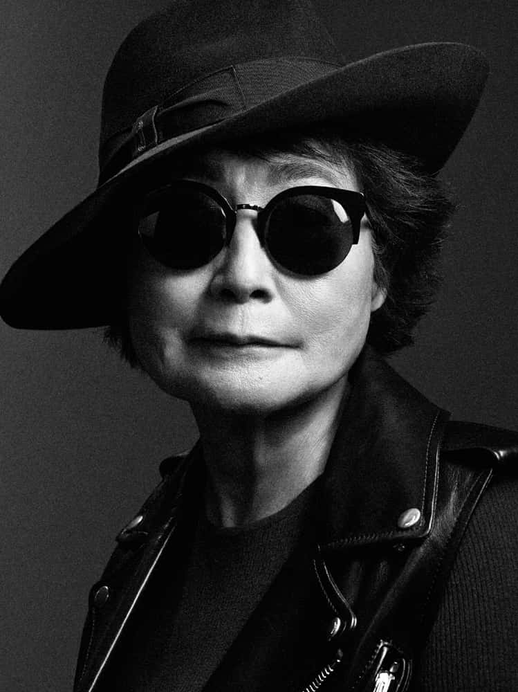 復古 桌布 壁紙 — 一位年長女性戴著寬邊帽和圓形太陽眼鏡，身穿皮夾克，散發著沉穩自信的黑白肖像照。