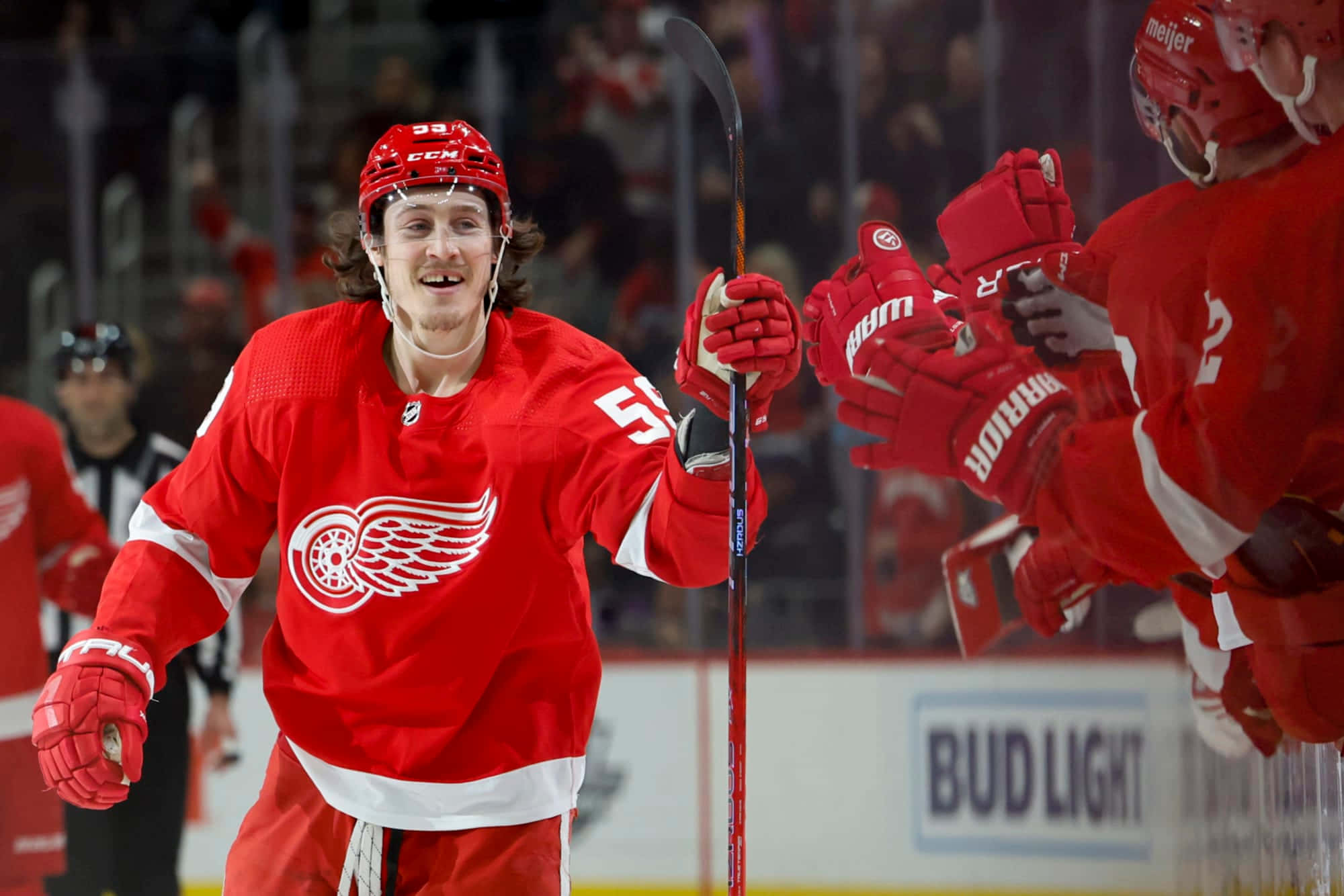 Tyler Bertuzzi 桌布 壁紙 — 一位底特律紅翼冰球球員身穿紅色裝備，在冰上與隊友慶祝時露出燦爛笑容。