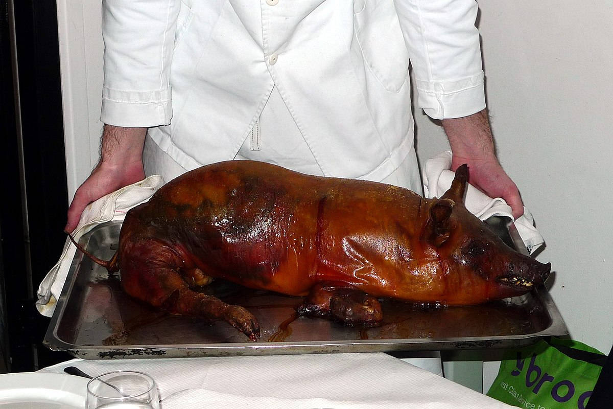 Pig 桌布 壁紙 — 一位廚師自豪地展示放在金屬托盤上的整隻烤豬，外皮金黃酥脆。