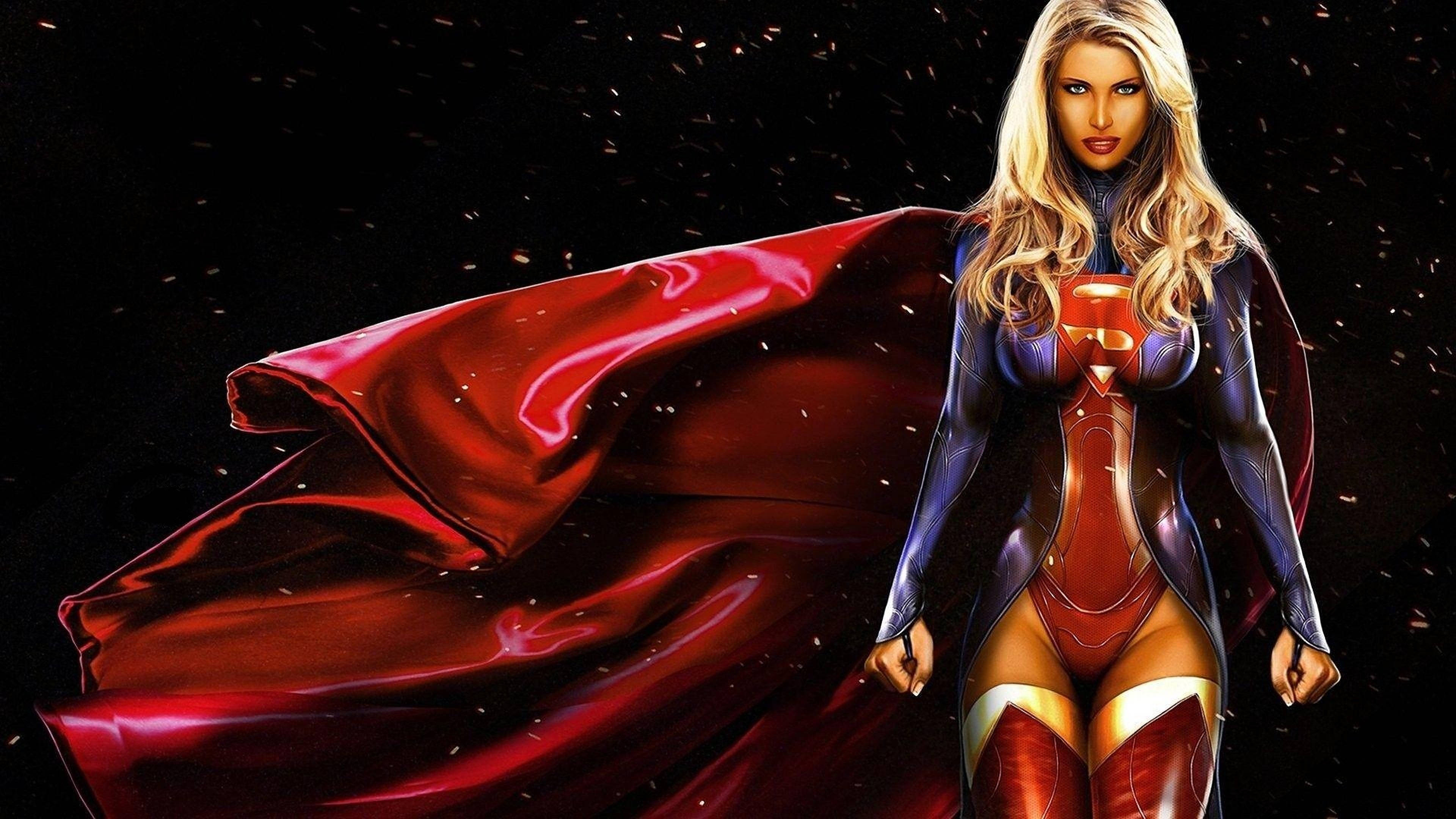 Superwoman 桌布 壁紙 — 一位強大的女性超級英雄，身穿紅藍色緊身衣，披著飄逸的紅色斗篷，在充滿漂浮粒子的黑暗宇宙背景前自信地站立。
