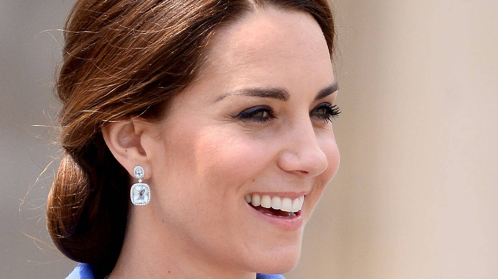 Kate Middleton 桌布 壁紙 — 一位微笑女士的頭像近照，棕色頭髮盤成髮髻，佩戴優雅的鑽石耳環。
