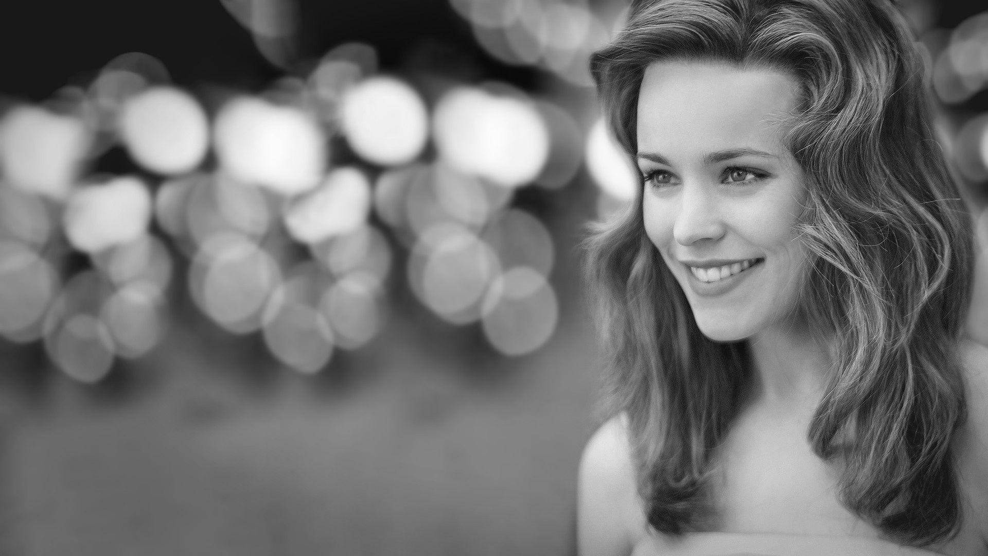 Rachel Mcadams 桌布 壁紙 — 一位微笑女士的黑色和白色肖像，波浪頭髮，背景模糊散景。