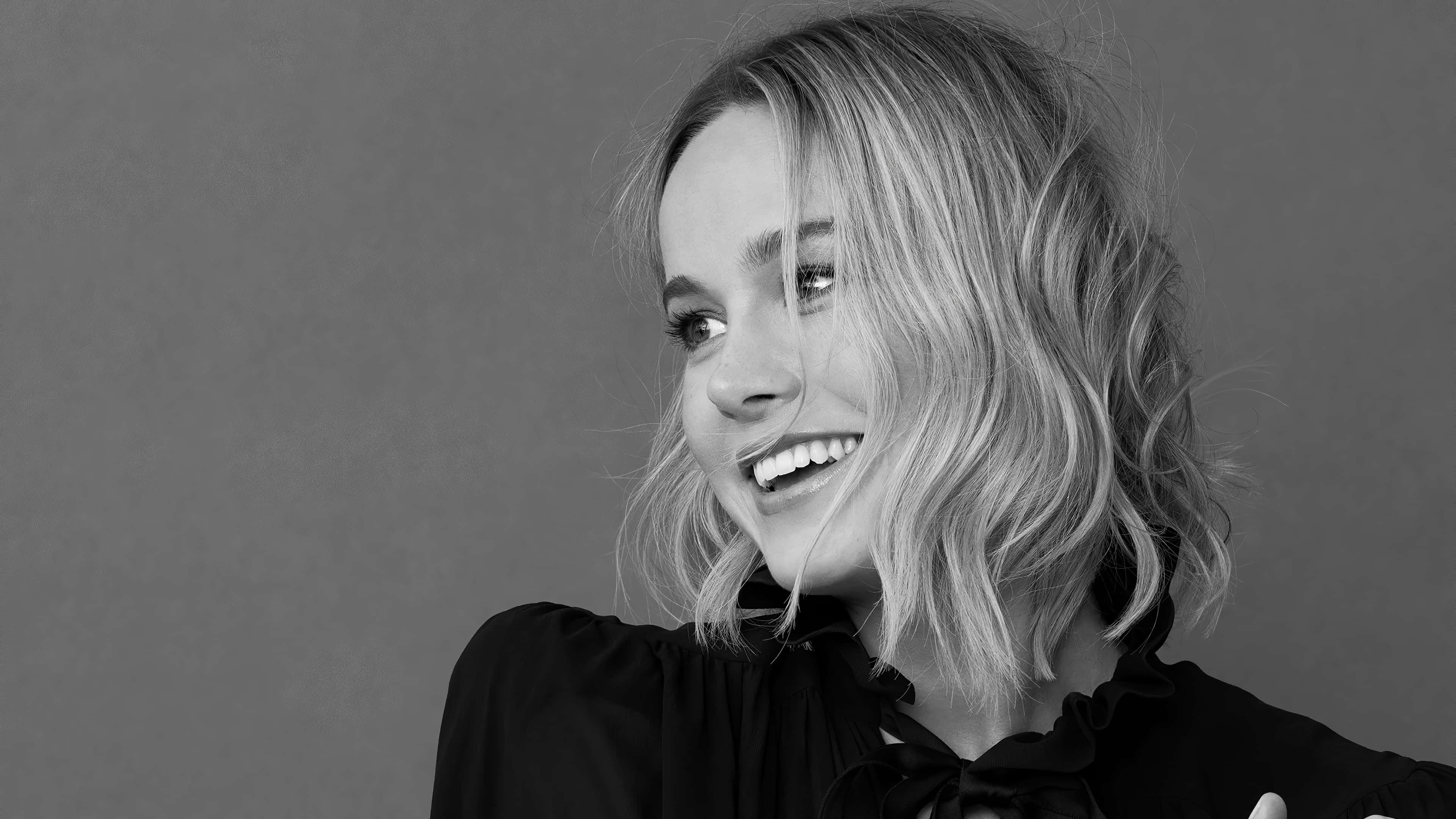 brie larson 桌布 壁紙 — 一位微笑女性、波浪波波頭髮、在純灰色背景前的黑白肖像。