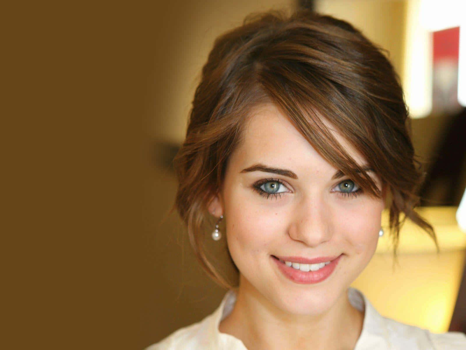 lyndsy fonseca 桌布 壁紙 — 一位微笑女性的特寫肖像，擁有引人注目的藍色眼睛和柔軟波浪造型的棕色頭髮。