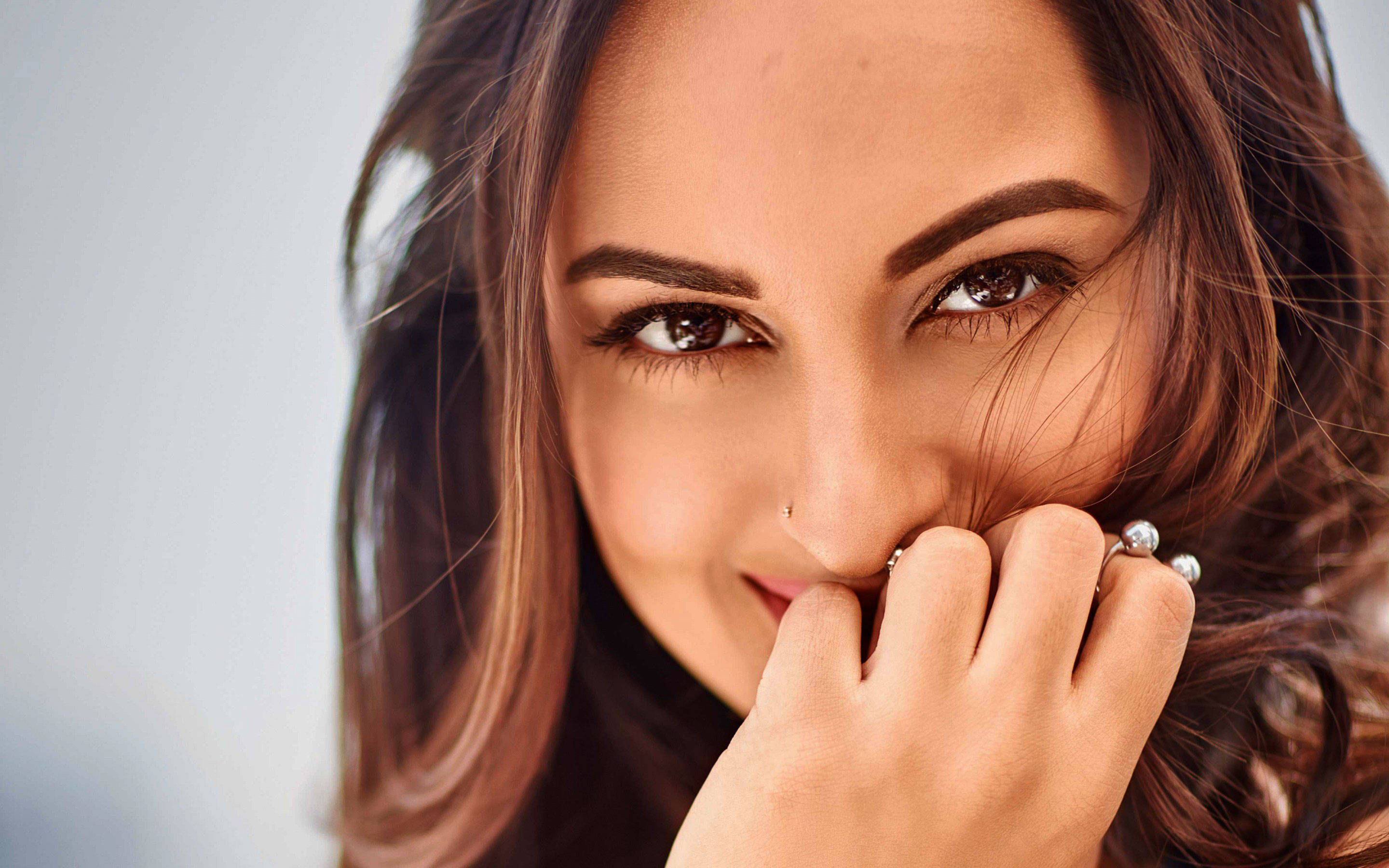 Sonakshi Sinha 桌布 壁紙 — 一位微笑女性的特寫肖像，深色頭髮和戒指輕輕放在她的嘴唇上。